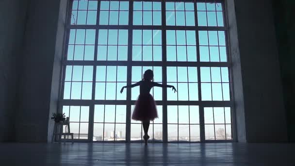 一个芭蕾舞演员的剪影在一个大窗口的背景。芭蕾舞者用尖角鞋旋转 — 图库视频影像
