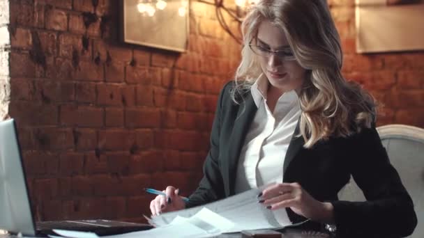 Zakenvrouw werken met documenten in het kantoor in de kracht van een loft. een meisje in zakelijke kleding en dragen bril. zakelijke make-up en kapsel — Stockvideo