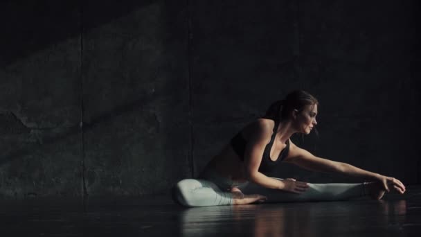 Chica haciendo estiramiento sentado en una cuerda. gimnasta para el entrenamiento. atractiva joven en ropa deportiva se dedica al yoga . — Vídeo de stock