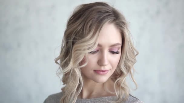 Close-up πορτρέτο της μια ελκυστική ξανθιά. νεαρό κορίτσι με ένα ελαφρύ μέικ-απ και μπούκλες — Αρχείο Βίντεο