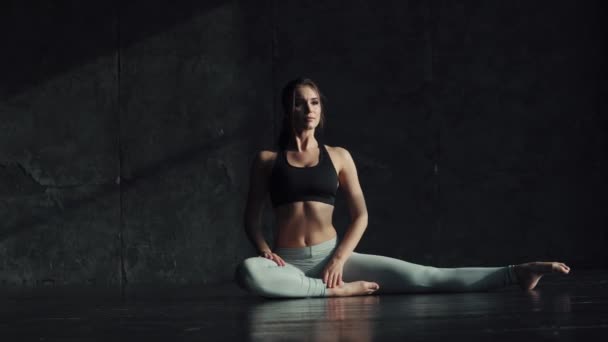 Chica haciendo estiramiento sentado en una cuerda. gimnasta para el entrenamiento. atractiva joven en ropa deportiva se dedica al yoga . — Vídeo de stock