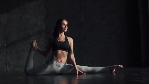 Девушка делает растяжку сидя на веревке. гимнастка для тренировок. привлекательная молодая женщина в спортивной одежде занимается йогой . — стоковое видео