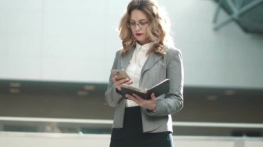 iş kadını notlar onun not defterinde arıyor. Kız bir ofis binasının lobisinde gri ceket