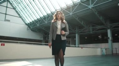 gri bir ceket ve etek genç bir kadın ofis binası lobi yürür. kendinden emin bir iş kadını. ağır çekim