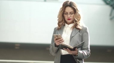 iş kadını smartphone--dan bir ileti gönderir. iş takım elbiseli kız telefonu cevap vermiyor. iş merkezinin lobide genç bir kadın portresi