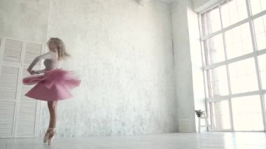 Bale dansçısı büyük bir ışık pencere arka planı dönüyor. bir klasik tutu ve pointe balerin. ağır çekim