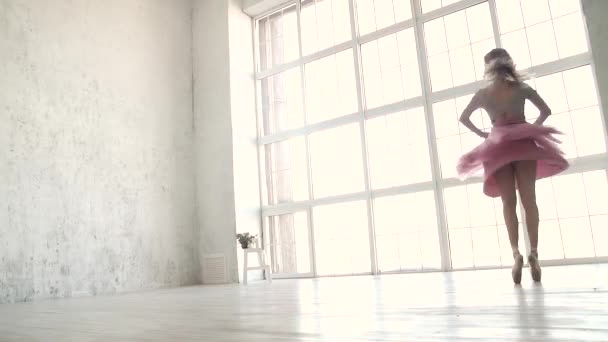 Bailarina de ballet girando dinámicamente contra el fondo de una gran ventana brillante. bailarina en un tutú clásico y zapatos Pointe — Vídeo de stock