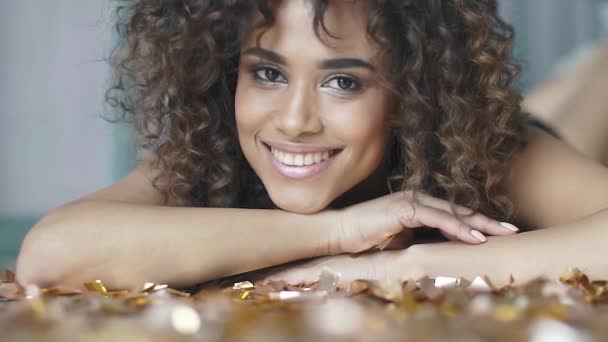 Närbild porträtt av en spansktalande tjej med ett charmigt leende. multietniskt flicka ligger med konfetti. konceptet för semester, kul, fira. slowmotion — Stockvideo