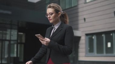iş kadını sokakta yürürken ve smartphone ileti gönderme. ağır çekim