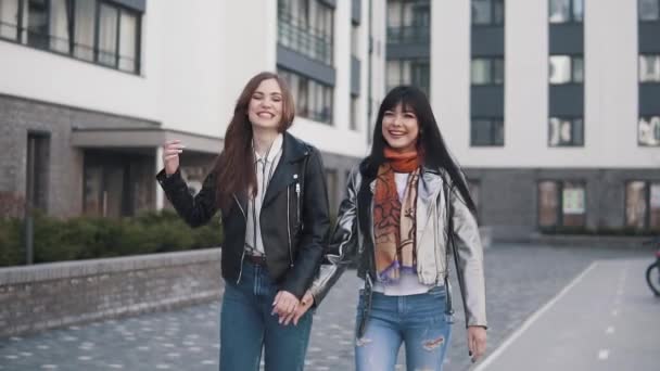 Веселі дівчата гуляють по весняному місту, сміються, посміхаються і обіймаються. повільний рух — стокове відео