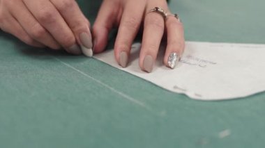 kadın bir desen kumaş üzerine uyguluyor. Giysi Tasarımcısı tebeşir dokusu üzerinde çizer.