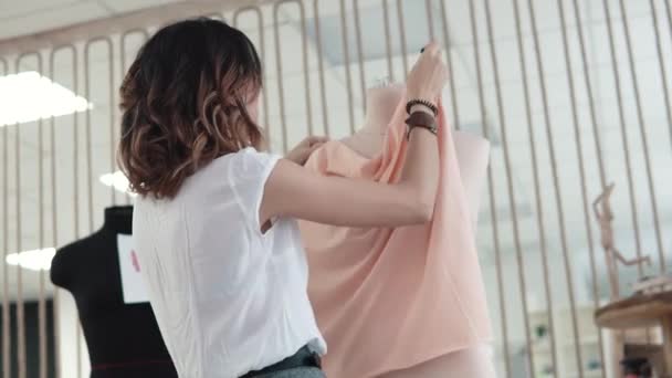 Ασιατικό κορίτσι ρούχα σχεδιαστών συλλέγει ένα μοντέλο ρούχα σε ένα μανεκέν — Αρχείο Βίντεο