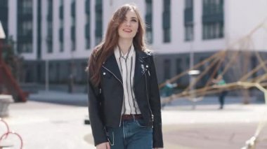 Genç bir kız onun ceketini çıkar şehrin her yerinde ve hareket alır üzerinde yürür. modern mimarinin bir arka plan güzel bir genç kadının portresi. ağır çekim