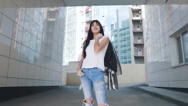 Fashionable girl in jeans and a shiny jacket. portrait of a girl with a beautiful smile. slow motion — Stock Video