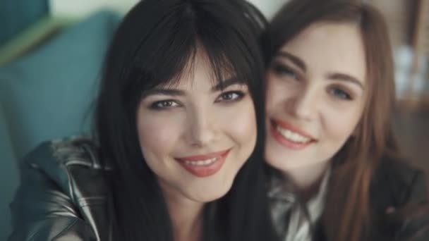 Flickvänner göra selfie på mobilkameror medan du sitter på ett café. två attraktiva tjejer ta bilder på kameran på din smartphone och lura runt — Stockvideo