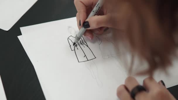 Desenhista de roupa faz um esboço da roupa com uma caneta de hidrográfica. mãos femininas close-up — Vídeo de Stock