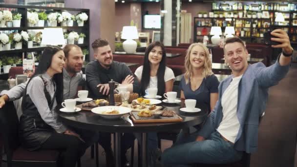 Велика група друзів змушує селфі сидіти за столом у кафе або ресторані . — стокове відео