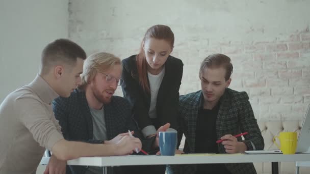 Equipe de empresários discutir um projeto enquanto se senta em uma mesa no escritório. colegas estão olhando através de documentos e conversando — Vídeo de Stock