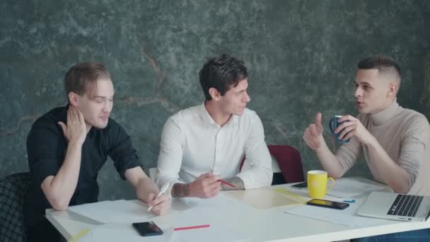 Colegas se divertir conversando durante uma pausa no escritório. três jovens bebem café e conversam — Vídeo de Stock