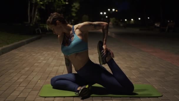 Atletyczna dziewczyna robi rozciąganie w parku wieczorem — Wideo stockowe
