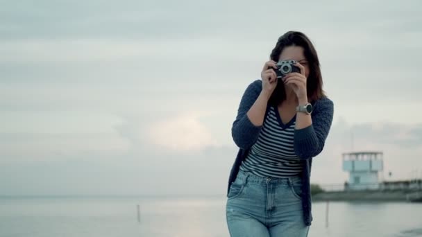Mujer joven toma fotos en una cámara retro al aire libre . — Vídeos de Stock