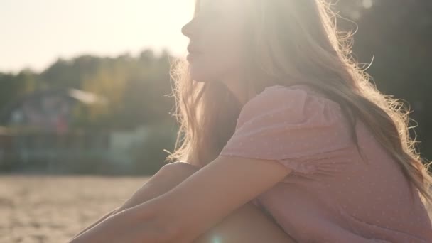 Charming young woman sits on the sand at the beach — Stock Video