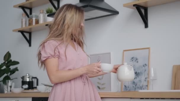 Schöne Mädchen mit einem charmanten Lächeln gießt Tee aus einer Teekanne — Stockvideo