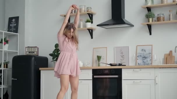 Щаслива і безтурботна дівчина танцює смішно на кухні — стокове відео