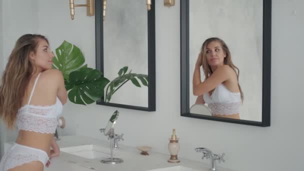 Милая девушка в нижнем белье танцует и одевается перед зеркалом в ванной — стоковое видео
