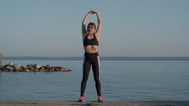 Ragazza si sta riscaldando la mattina presto sulla riva del mare — Video Stock