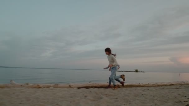 Kinder laufen bei Sonnenuntergang an der Küste entlang — Stockvideo