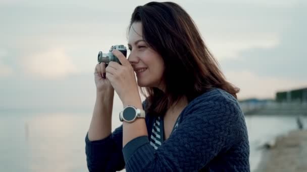 Молодая женщина фотографирует на ретро-камеру на открытом воздухе . — стоковое видео
