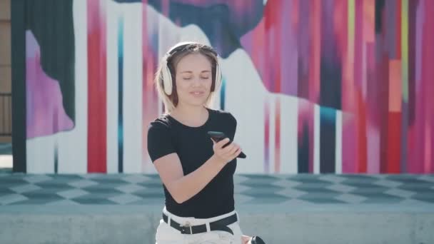 Chica divertida divirtiéndose bailando escuchando música de teléfono en auriculares grandes — Vídeo de stock