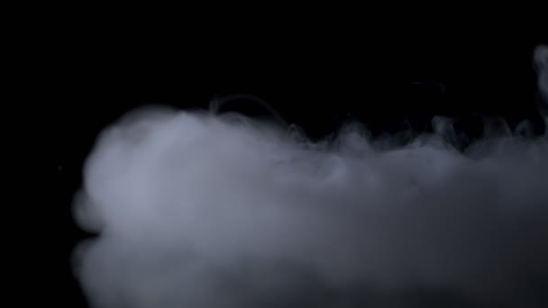 Biały dym powoli unosi się w przestrzeni na czarnym tle. Efekt mgły. Dym atmosferyczny. Mglista przeszłość. Abstrakcyjna chmura dymu. — Wideo stockowe
