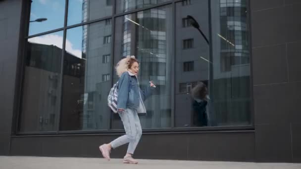 Grappig en zorgeloos meisje gaat dansen rond de stad. krullend blond gek dansen buitenshuis. — Stockvideo