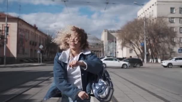 Ragazza riccia divertimento ballando passeggiando per la città. spensierato adolescente sorride e si diverte . — Video Stock