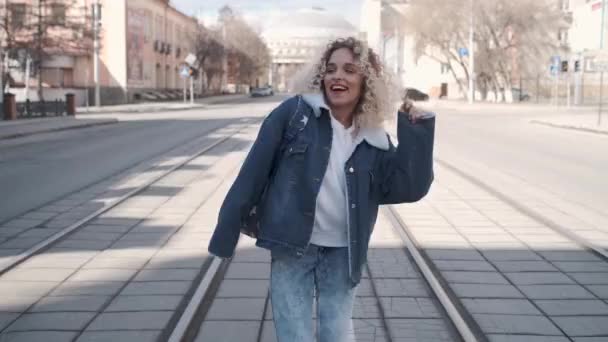 Menina alegre despreocupado andando pela rua e sorrindo. uma jovem compartilha seu bom humor com os outros . — Vídeo de Stock