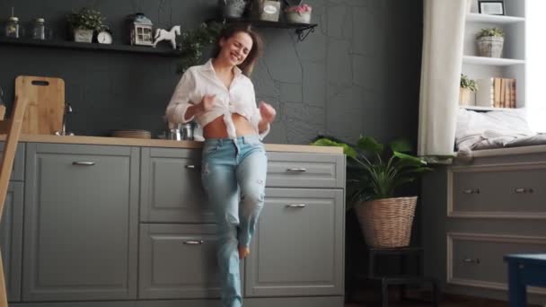 Mujer feliz se regocija levantando las manos y sonriendo. chica divirtiéndose y bailando en casa en la cocina — Vídeo de stock