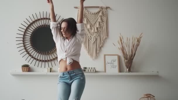 Fille heureuse qui s'amuse à danser à la maison. jeune femme danse insouciante avec les bras levés — Video