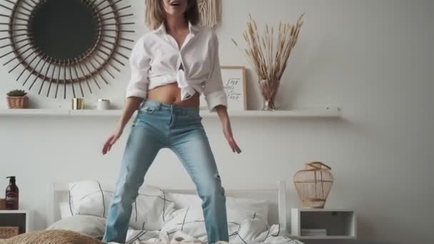 Chica feliz bailando en casa de pie en la cama. joven mujer despreocupada baila y disfruta de la vida — Vídeo de stock