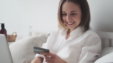 Mutlu kadın internetten alır ve gülümser. Kız dizüstü bilgisayardan kredi kartı numarasını giriyor. İnternetten alışveriş kolik alışverişler