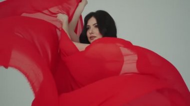 Kırmızı elbiseli bir kadın. Kumaş rüzgarda sallanıyor. Reklam parfümleri ya da diğer kavramlar için modaya uygun bir görüntü.