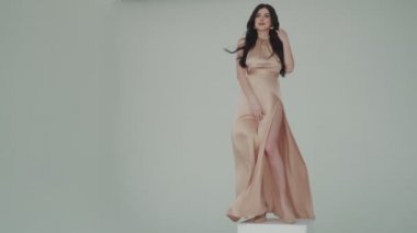 Gece elbisesi içinde rüzgârda çırpınan çekici bir kız. Güzel makyajlı ve kameraya poz veren genç bir kadın. Reklam parfümleri ya da diğer kavramlar için modaya uygun bir görüntü.