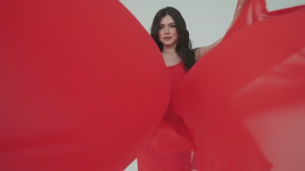 Jasna młoda kobieta w czerwonej sukience. Dziewczyna z tkaniną w rękach. modny wizerunek perfum reklamowych lub innych pojęć. — Wideo stockowe