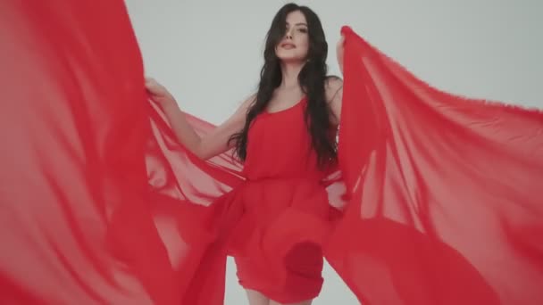 Портрет пристрасної молодої жінки в мерехтливій червоній сукні. дівчина з тканиною в руках. модний образ для реклами парфумів або інших концепцій . — стокове відео