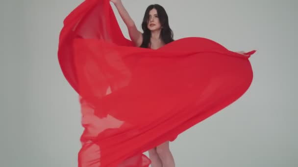 Портрет пристрасної молодої жінки в мерехтливій червоній квітковій сукні. дівчина з тканиною в руках. модний образ для реклами парфумів або інших концепцій . — стокове відео