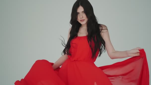 Detailní portrét vášnivé ženy v třepetavých červených šatech. dívka s látkou v rukou. módní image pro reklamní parfémy nebo jiné koncepty. — Stock video