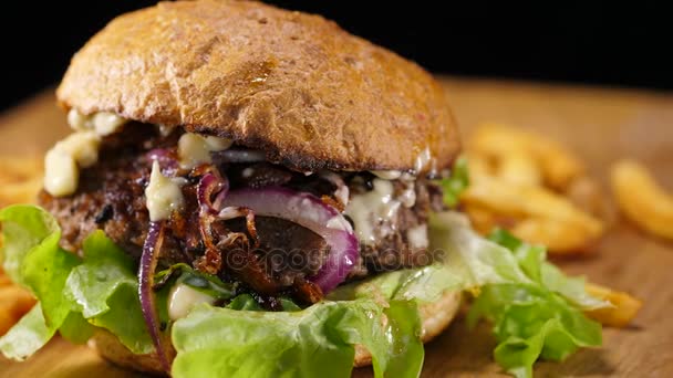 Primer plano de una hamburguesa a la parrilla con cebolla y papas fritas — Vídeo de stock