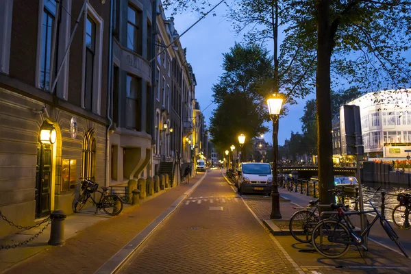 The Sidewalks at the canals of Amsterdam by night - AMSTERDAM - THE NETHERLANDS - JULY 20, 2017 — стоковое фото