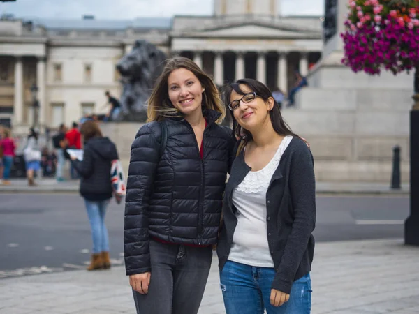 Dvě dívky pózuje pro fotografie na Trafalgar Square v Londýně — Stock fotografie